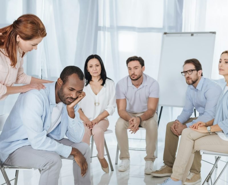 psychotherapist supporting african american man during group therapy